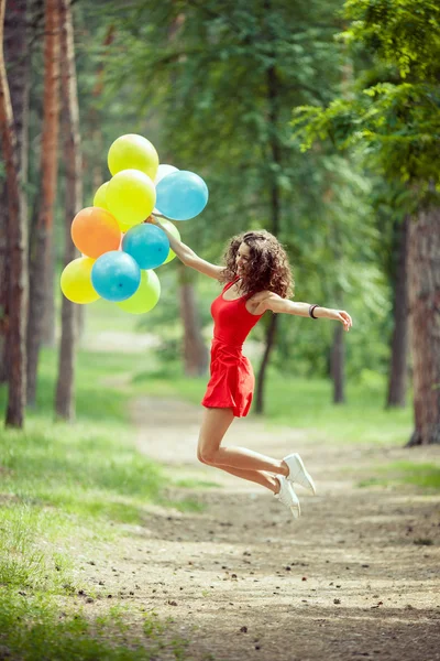 Vacker ung tjej att ha kul på sommaren parken med färgade ballonger. Lyckligt leende hoppa koncept Royaltyfria Stockbilder