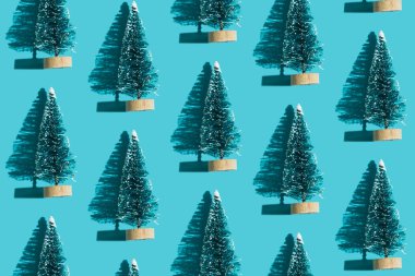 Mavi arka planda oyuncak plastik ağaç. Sert gölgeli bir Noel ağacı deseni. Noel ve yeni yıl kompozisyonu tatiller için. Düz yatıyordu. Üst görünüm.