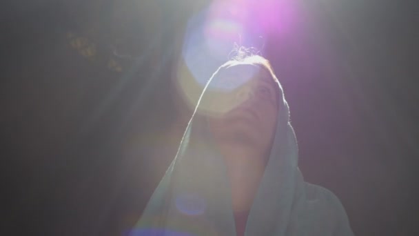 Νεαρή χιλιετή γυναίκα με ροζ φόρεμα και μπλε μαντίλα στέκεται στην εκκλησία, ναός και προσεύχεται, κοιτάζει την κάμερα με μια σοβαρή έκφραση. Αργή κίνηση. — Αρχείο Βίντεο