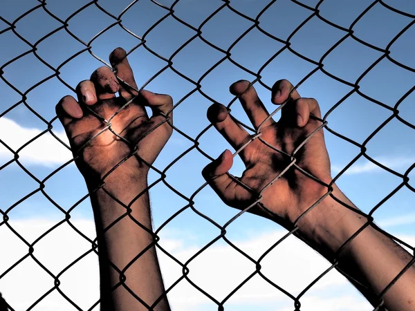 Dirty and discolored hands clinging to a steel wire fence — Stock Photo, Image