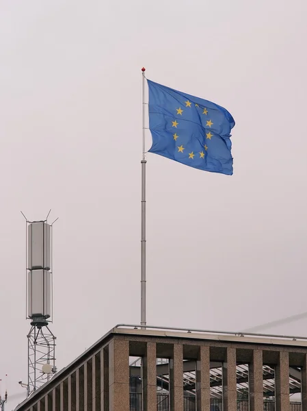 De vlag van de Europese Unie naast een mobiele telefoon toren op een gebouw op een sombere dag — Stockfoto