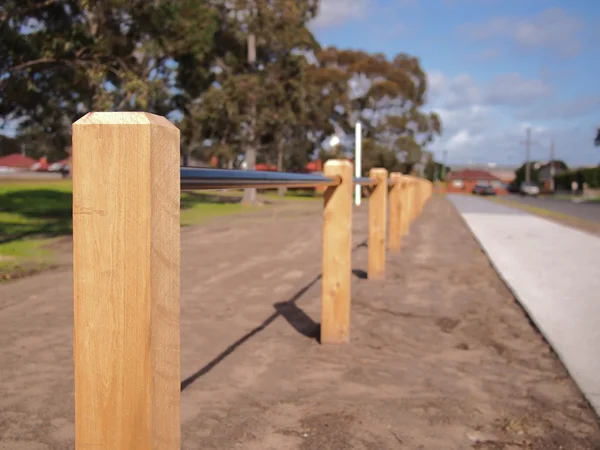 Timmer barriär pole och barriär tube bewteen en väg och en offentlig park — Stockfoto