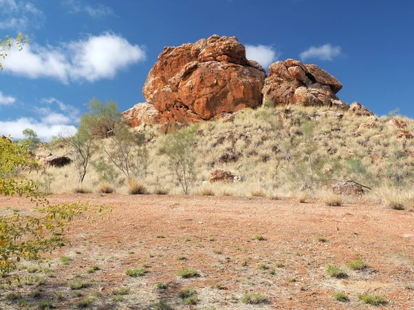 Tmavě červená outback skalní útvar pod modrou oblohou nedaleko Alice Springs — Stock fotografie