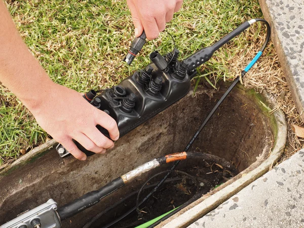 Installer plugging in a fibre optic cable — Stockfoto