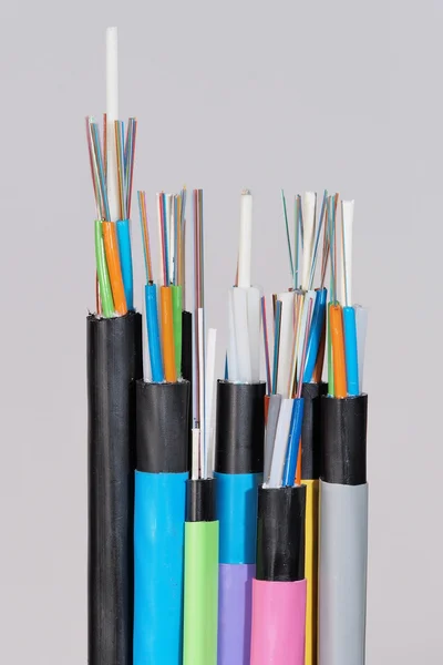 Group of 7 different fiber optic cable  ends with stripped jacket layers and exposed colored fibers, straight view — Stock Photo, Image