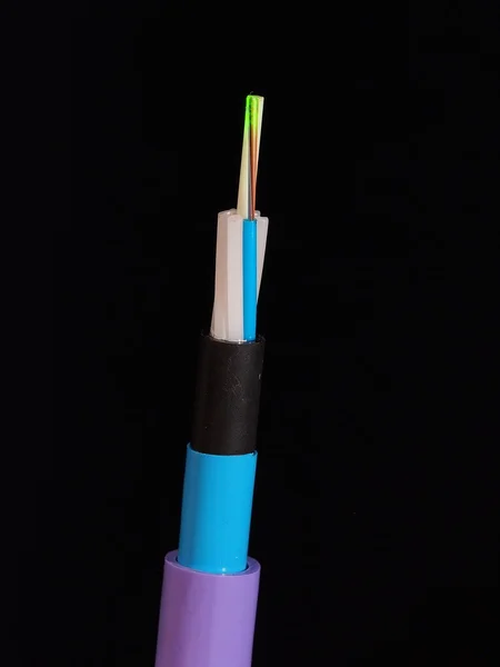 Violet jacketed fiber optic cable with stripped and exposed fibers lit by green laser light in front of a black background — Stock Photo, Image