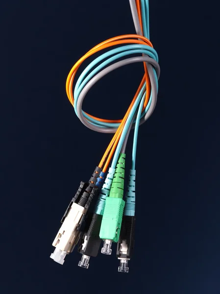 A bundle of three fiber optic patch cords with connectors arranged in a knot on black background — Stock Photo, Image