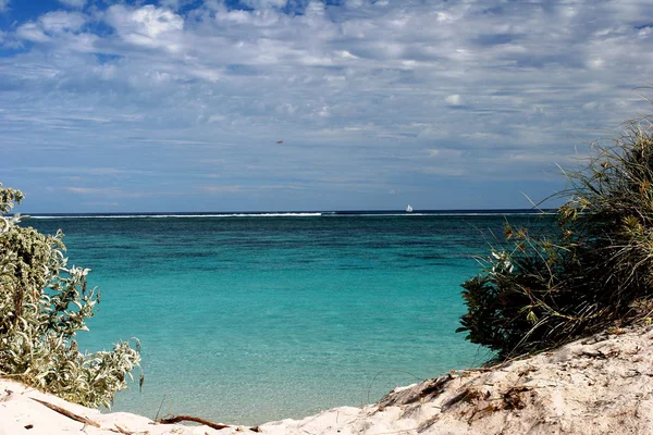 Pristine turquois waters through gap in the dunes