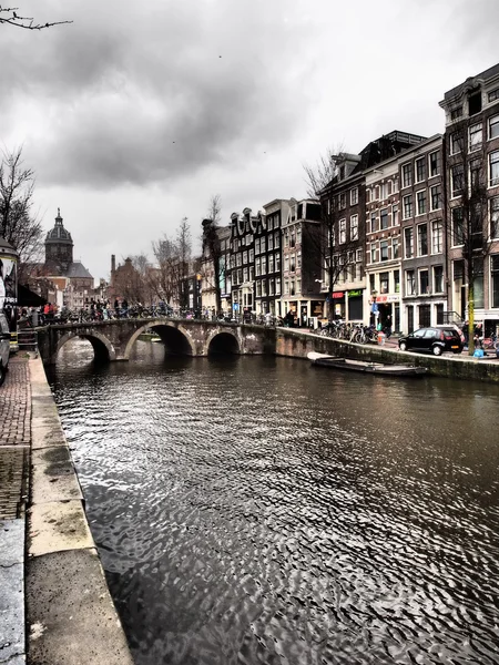 Amsterdam canal wall and bridge with dramatic clouds — 图库照片