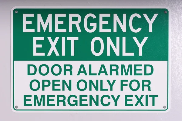 Emergency exit wall sign in green on off white — Stock Photo, Image