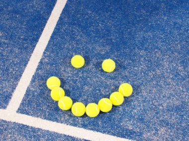 Gülen bir mavi suni çim kortta tenis topları