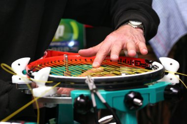 Racquet stringer weaving cross strings of synthetic gut string in a Tennis racquet clipart