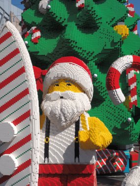 Giant Toy Santa in front of a Christmas tree and a surfboard clipart