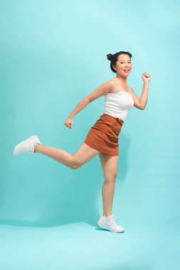 Turkuaz arka planda atlayan genç bir kadın.