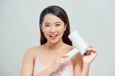 Gülümseyen genç kadın fön çekerken şarkı söylüyor