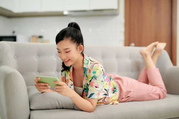 Усміхнена Молода Азіатка Використовуючи Мобільний Додаток Грає Гру Розслабляється Дивані — стокове фото