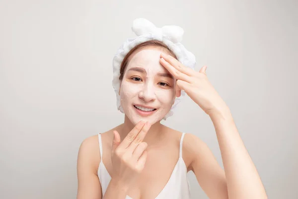 年轻女人在脸上涂润肤霜 照片上的微笑女性正在接受温泉治疗 打扮自己 — 图库照片