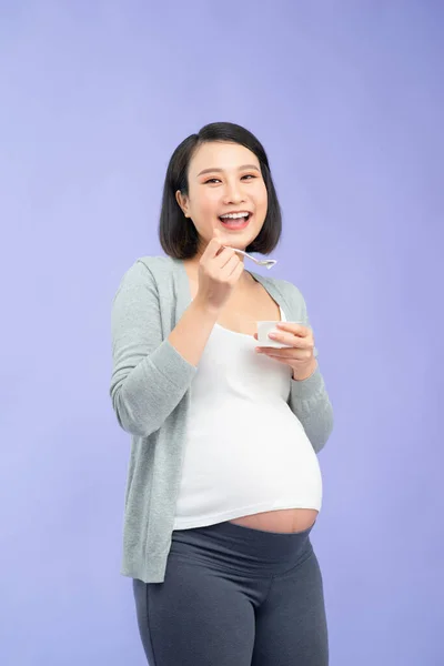 임신부가 보라색 위에서 플라스틱 컵에서 요구르트를 — 스톡 사진