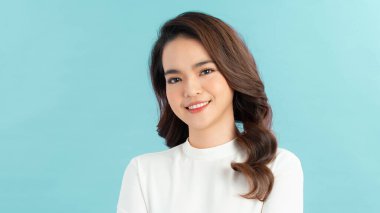 Güzel, neşeli, sarışın, sıradan giyinmiş, kameraya tatmin olmuş, mutlu bir şekilde bakan bir kadın.