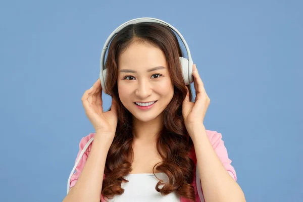 年轻美丽的亚洲女孩在五颜六色的蓝色背景下听音乐的肖像 — 图库照片