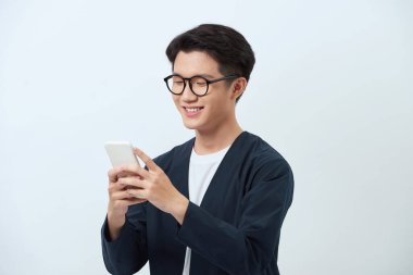 Gülümseyen yakışıklı Asyalı adam akıllı telefon kullanıyor. 