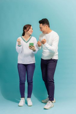 Asyalı genç çift, izole edilmiş bir geçmişe sahip akıllı bir telefon görüşmesinin ekranına bakıyor.