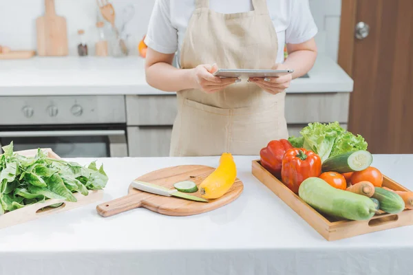 Happy woman looking recipe tablet kitchen reading cooking