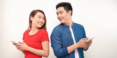 Heyecanlı ve şaşırmış bir çiftin görüntüsü beyaz arka planda cep telefonuyla izole edilmiş..