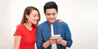 Heyecanlı ve şaşırmış bir çiftin görüntüsü beyaz arka planda cep telefonuyla izole edilmiş..