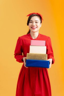 Genç Asyalı kadının portresi turuncu arka planda hediye kutularını tutuyor..