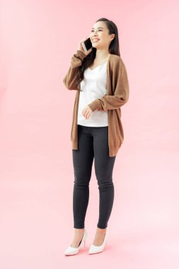 Uzun boylu, mavi arka planda cep telefonuyla konuşan genç bir kadın.