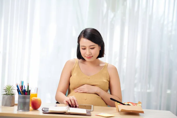 Una Mujer Embarazada Sienta Una Mesa Usa Una Tableta — Foto de Stock