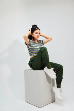 Gündelik giysiler içinde, arka planda, sandalyede oturan güzel genç bir kadın.