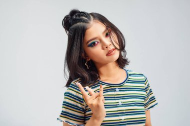 Beyaz arka planda boynuz işareti yapan genç punk kadın.