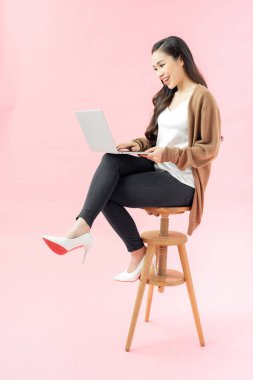 Mavi arka planda dizüstü bilgisayarla gülümseyen güzel bir genç.