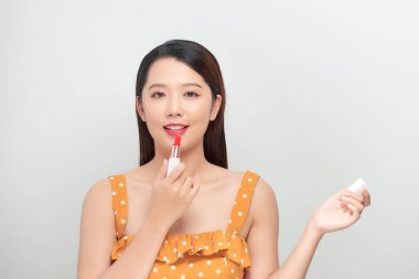 Gülümseyen güzel bir kadın ruj sürüyor.