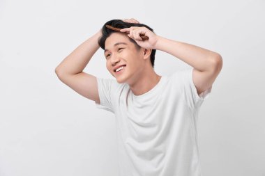 Yakışıklı, gülümseyen genç adam modern saç stili yapıyor.