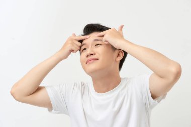 Sivilce tedavisi. Sivilceli adam sivilcelerini sıkıyor, sivilcelerini yüzünden çıkarıyor.