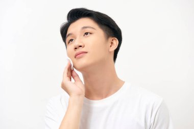 Pamuklu çubukla yüzünü temizleyen yakışıklı genç adam (beyaz arka planda izole edilmiş))