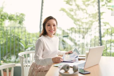 Beauitul genç kadın bilgisayarla çalışıyor konsantre ve gülümsüyor.