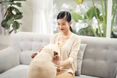 Kanepede oyuncak bir köpekle oturan kadın.