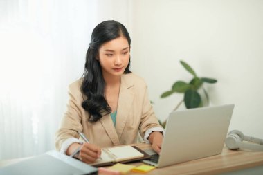 Mutlu, neşeli, güzel iş kadını imajı. Ofiste dizüstü bilgisayar kullanarak oturuyor. 