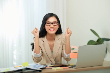 Asyalı kadın evde çalışıyor ve kahve içiyor. Başarılı bir işten memnun.