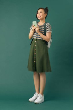 Öğrenci kadın yeşil arka planda cep telefonu kullanıyor