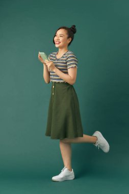 Öğrenci kadın yeşil arka planda cep telefonu kullanıyor