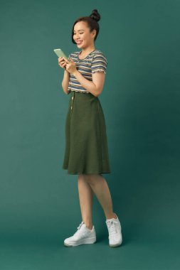 Çekici, neşeli, etkileyici bayan. Telefonu yeşil arka planda sırt çantasıyla tut.