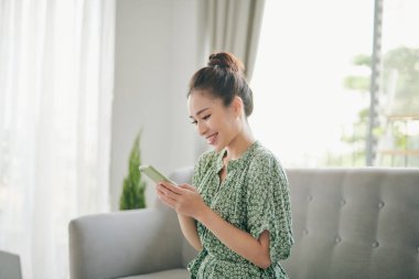 Çekici Vietnamlı kadın akıllı telefonunda uygulama kullanıyor.