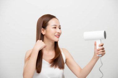 Güzel Asyalı kız saçını saç kurutma makinesiyle kurutuyor..