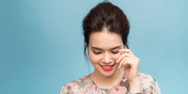 Mavi arka planda soyutlanmış, gülümseyen zarif, güzel bir Asyalı kadın.