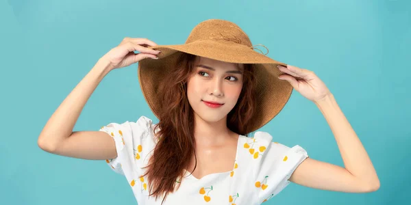 夏の帽子をかぶったクールな女性がカメラと笑顔を見て 青いスタジオの背景にポーズ — ストック写真